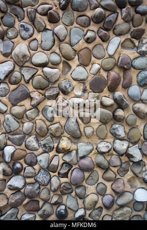 A closeup of a wall made from smooth stones embedded in cement mortar Stock Photo