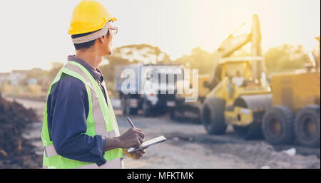 Asian engineer with hardhat using  tablet pc computer inspecting and working at construction site Stock Photo