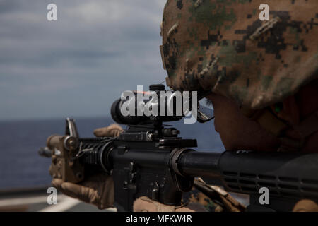 A Marine with Combat Logistics Battalion 31 shoots an M4 carbine service rifle on the flight deck of the USS Ashland (LSD-41) while underway in the Pacific Ocean, April 11, 2018. Marines with the 31st Marine Expeditionary Unit improved their precision and ability to fire quickly after sighting in at short range. CLB 31 is the Logistics Combat Element of the 31st MEU. As the Marine Corps’ only continuously forward-deployed MEU, the 31st MEU provides a flexible force ready to perform a wide range of military operations. (U.S. Marine Corps photo by Lance Cpl. Matt Navarra/Released) Stock Photo