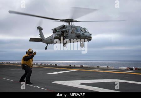 180424-N-WF272-177 PACIFIC OCEAN (April 24, 2018) Aviation Boatswain’s Mate (Handling) Airman Richard Moomey, from Cedar Rapids, Iowa, signals to launch an MH-60S Seahawk helicopter, assigned to the “Sea Knights” of Helicopter Sea Combat Squadron (HSC 22), during flight operations aboard the amphibious assault ship USS Bonhomme Richard (LHD 6). Bonhomme Richard, which had been forward-deployed since 2012 as the Amphibious Force 7th Fleet flagship, is transiting to San Diego as part of a homeport change and where it is scheduled to undergo upgrades to operate the F-35B Lightning II. (U.S. Navy  Stock Photo