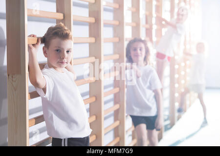 Young kids working out with wall bars at a school gym Stock Photo