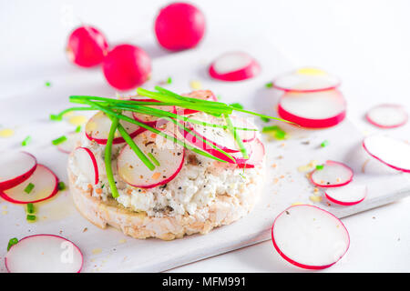 Easy breakfast concept with crisp bread, radish slices, scallion, cottage cheese and pepper. Healthy snack in high key with copy space. Stock Photo