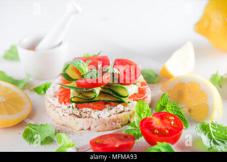 Crisp bread healthy snack with salmon, cottage cheese, cucumber stripes, fresh cherry tomatoes, mint, lemon juice, pepper. Easy breakfast close-up on  Stock Photo