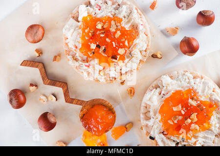 Crisp bread snack with Feta cheese, apricot jam and hazel nuts. Easy breakfast close-up on a white background with copy space. Stock Photo