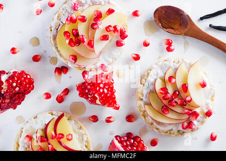 Crisp bread healthy snack with apple slices, soft cottage cheese, vanilla, honey, pomegranate seeds. Easy breakfast concept on a white background with Stock Photo