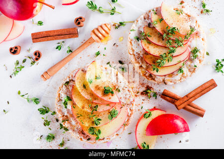 Crisp bread snack with apple slices, cinnamon, greek youghurt, honey and fresh thyme. Easy breakfast close-up on a white background with copy space. Stock Photo