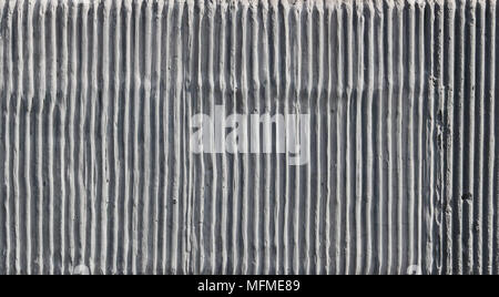 The wall of the old building is decorated with a texture of vertical cement uneven wavy strips. Sunny day outdoor shot Stock Photo