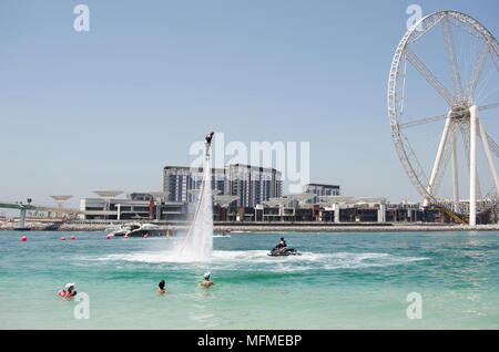 Dubai, United Arab Emirates - March 24, 2018.  Public city beach. Bathers observe the flight of a water jet motorcycle. Stock Photo