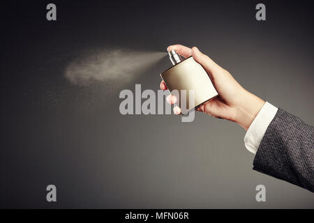 Man applying Perfume. Man's Perfume in the Hand on Black Background Stock Photo