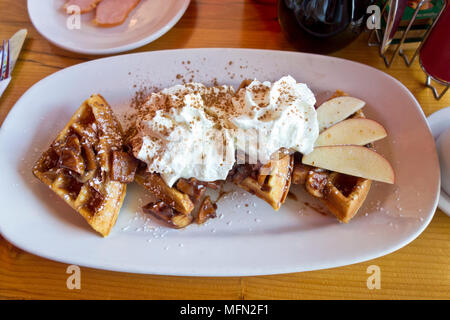 Fresh Belgian waffles with apples and cinnamon and whip cream topping served at Scandilicious restaurant in Vancouver Canada. Stock Photo