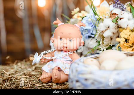 toy easter, painting eggs on a wooden bench in front of a wooden wall beside a flowering plant. happy easter. Stock Photo
