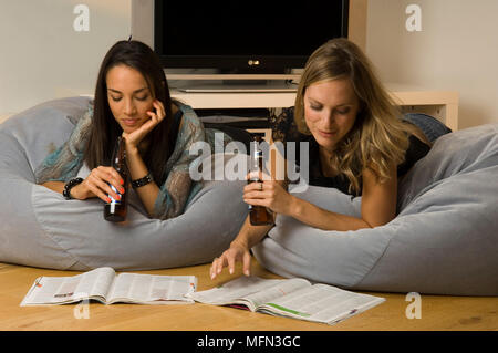 Two young women lying on bean bags and reading magazines   Ref: CRB410 10003 029  Compulsory Credit: Gary Moyes/Photoshot Stock Photo