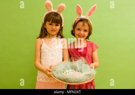 Portrait of two girls holding an easter basket filled with chocolate eggs   Ref:   Compulsory Credit: Stock Photo