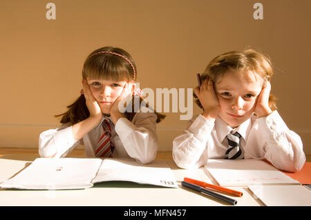 Portrait of two girls sitting at a table with their head in their hands   Ref:   Compulsory Credit: Stock Photo