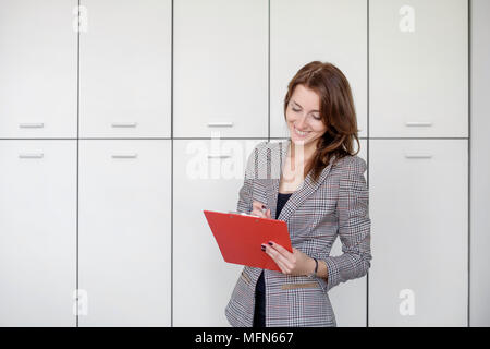 Busy female office worker going to make notes. Stock Photo