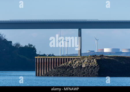 Wind turbines and oil storage tanks behind he NATO jetty and Cleddau bridge, Milford Haven Stock Photo