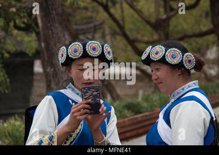 Lijiang, China - March 23, 2018: Chinese women wearing a traditional Bai minority attire using a smartphone in Lijiang, Yunnan Stock Photo