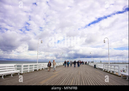 Dramatic clouds and people, walking along the pier (Molo), in Sopot, Poland. Built in 1827, it is the longest wooden pier in Europe Stock Photo