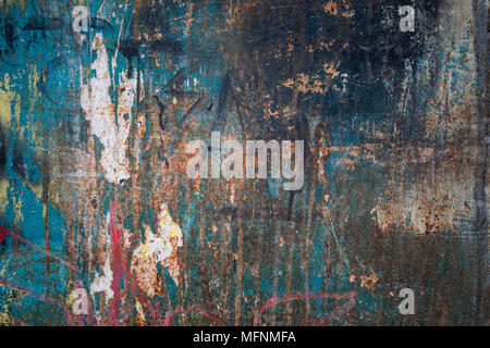 An abstract photograph of a metallic surface stained in light blue, red, yellow, black and white, with rusty areas. Stock Photo