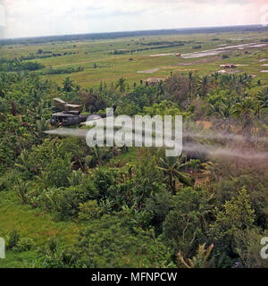 A UH-1D helicopter from the 336th Aviation Company sprays a defoliation agent on a dense jungle area in the Mekong Delta, 26 July 1969. Stock Photo