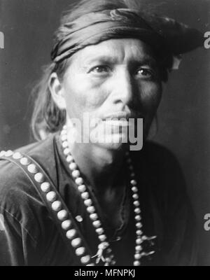 Head-and-shoulders portrait of Navajo man, facing slightly right, wearing headband and silver squash blossom necklace.1906. Photograph by Edward Curtis (1868-1952). Stock Photo