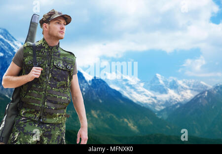 young soldier or hunter with gun over mountains Stock Photo