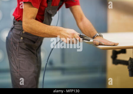 worker with glue gun and board at workshop Stock Photo