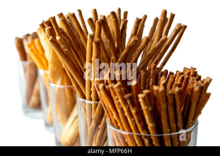 Row of pretzels, grissini and cheese sticks in glasses on white background. Stock Photo
