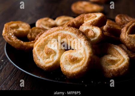 Palmier Cookies in Black Plate on Wooden Surface. Dessert Concept. Stock Photo