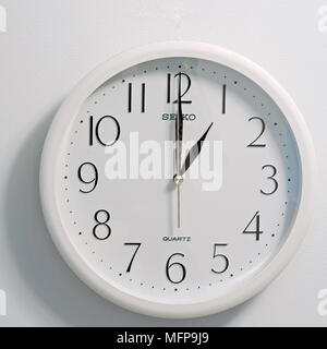 closeup of face of modern clock style showing round white and black dial at the time one o'clock on white background Stock Photo