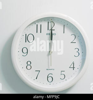closeup of face of modern clock style showing round white and black dial at the time twelve o'clock noon or midnight on white background Stock Photo