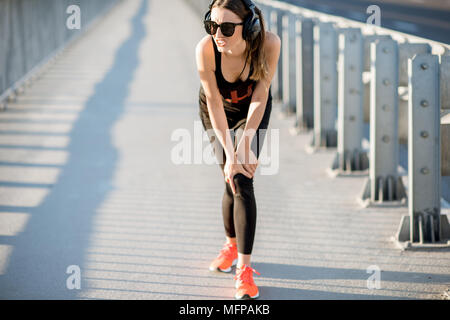 Woman having knee trauma during the morning run Stock Photo