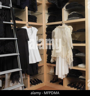 Detail of a modern bedroom, clothing storage featuring various black and white tops and dresses and a selection of high heeled shoes Stock Photo