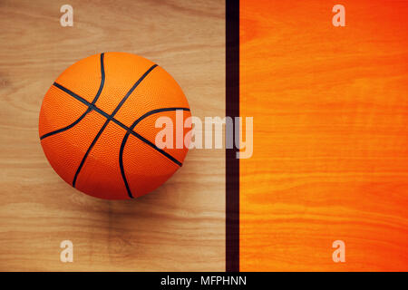 Basketball ball laying on hardwood court floor, top view Stock Photo