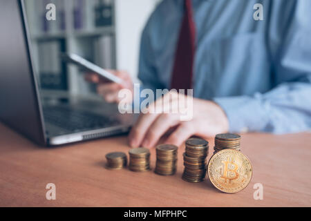 Bitcoin cryptocurrency trader, business person using modern technology electronic to trade with crypto money, stacked coins in the foreground and defo Stock Photo