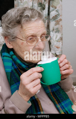 Elderly woman using a steam inhaler inhaling a decongestant for colds & bronchitis model release Stock Photo