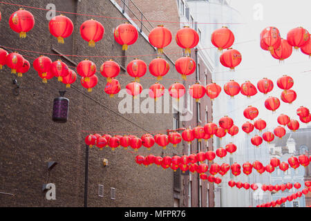 Red lanterns hang above the street, strung between buildings, in London UK's Chinatown district in celebration of Chinese New Year