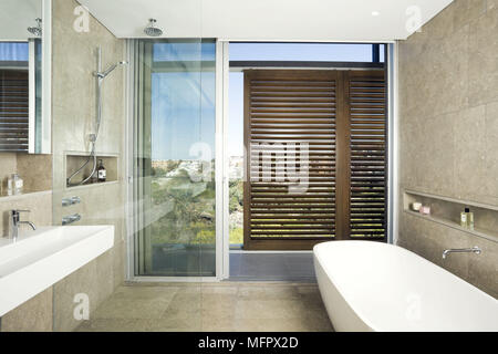 Freestanding bathtub in modern bathroom with sliding door to balcony area Stock Photo
