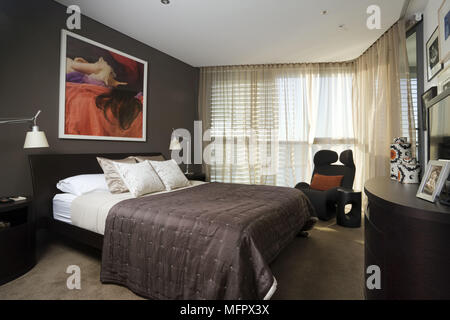 Lamps on bedside tables either side of double bed in modern bedroom Stock Photo