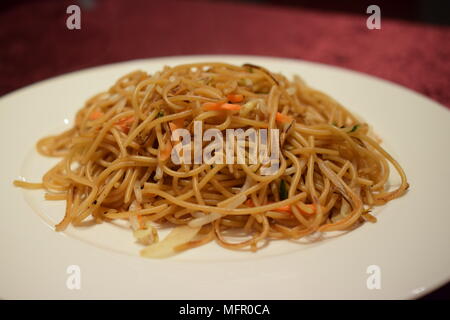 Chinese Lo Mein noodles dish with carrots and onions on a white plate Stock Photo