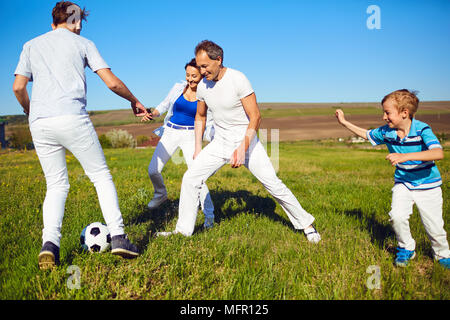 Happy family playing with a ball on nature in spring, summer. Stock Photo