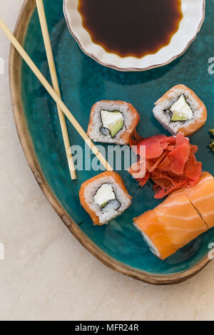 Top view shot of sushi, soy sauce and ginger in turquoise ceramic plate on marble tabletop. Stock Photo