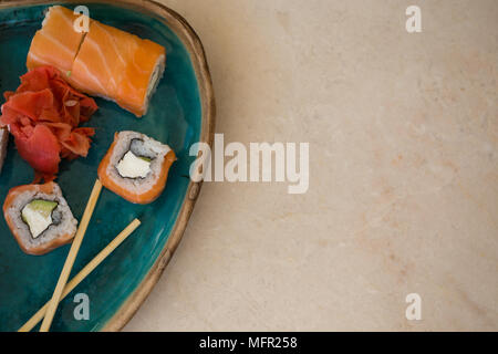 Top view shot of sushi and ginger in turquoise ceramic plate on marble tabletop. Copy space. Stock Photo