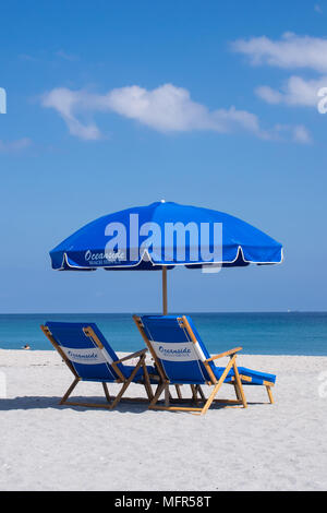 Relax in Delray Beach Florida on the sand, under an umbrella, with lounge chairs looking at the deep blue sea. Stock Photo