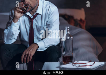 Man drinking whiskey in a suit while his woman is asleep Stock Photo