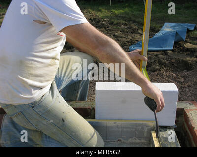 Builder / construction worker using a spirit level prior to cementing thermalite bricks model release Stock Photo