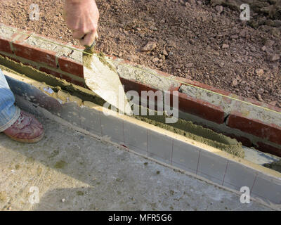 Builder / construction placing cementing in the space for thermalite bricks model release Stock Photo