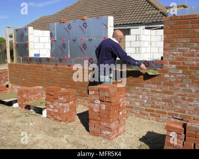 Builder / construction worker working on a brick wall cementing bricks in model release Stock Photo