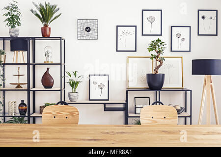 Simple gallery on a white wall in bright interior with wooden table and two chairs Stock Photo
