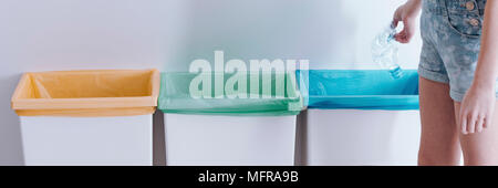 Header with colorful trash bags in recycling bins and a child throwing away a crushed plastic water bottle Stock Photo